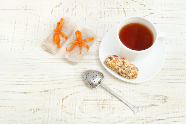 Vista superior de la taza de té y algunas barras de muesli. Fondo de madera blanca