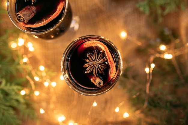 Vista superior de tazas de vino brillante con ramas de abeto y luces de guirnaldas