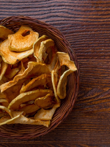 Vista superior del tazón con chips de manzana seca en la mesa de madera