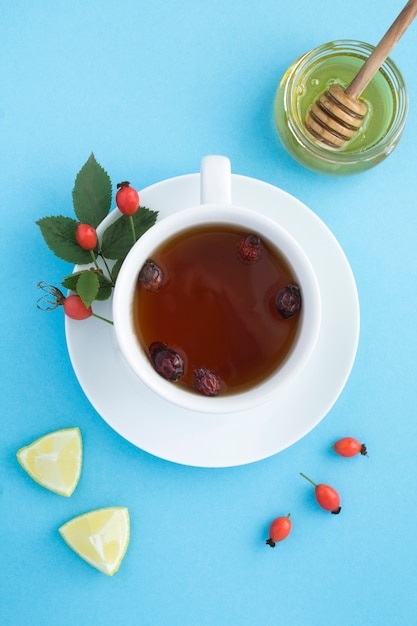 Vista superior de té con escaramujo y miel en la superficie azul