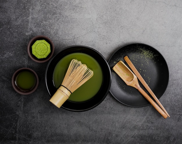 Foto vista superior del té matcha en un tazón con batidor de bambú y cuchara de madera