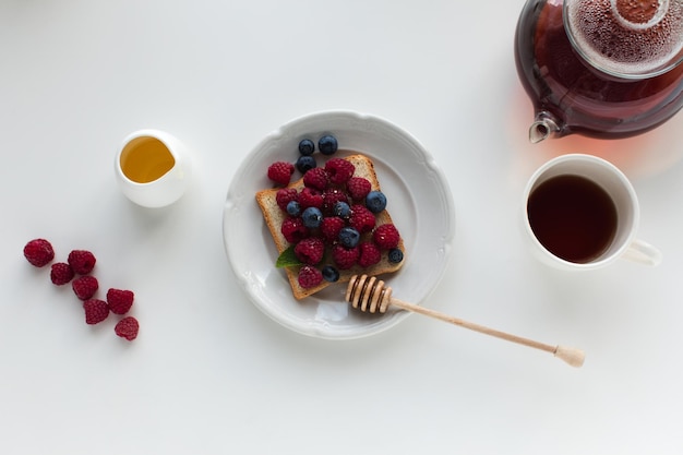 Vista superior de té y tostadas con bayas y miel para el desayuno aislado en blanco