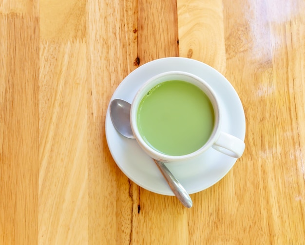 Vista superior del té verde matcha de leche condensada caliente servido en una taza blanca y un plato pequeño