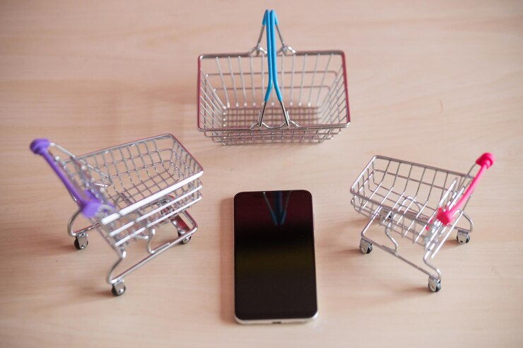 Foto vista superior en un teléfono móvil dos carritos de comida y una canasta en una mesa de madera compras en línea en un teléfono inteligente miniaturas