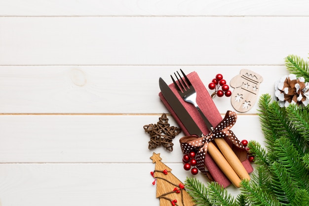 Vista superior de tenedor y cuchillo en servilleta con adornos navideños y árbol de año nuevo en madera, vacaciones y concepto festivo