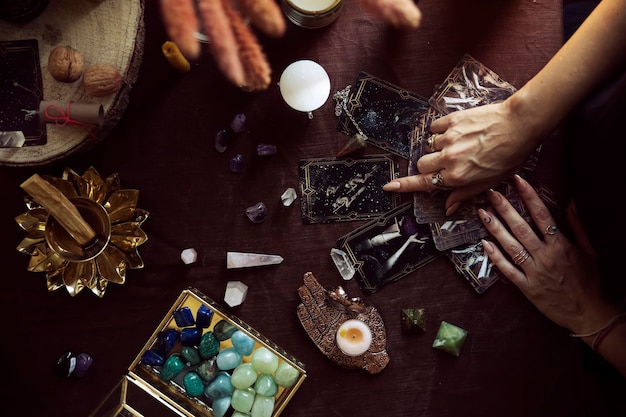 Vista superior de una tirada de cartas del tarot. Una mujer señala una de las cartas en su altar de brujas.