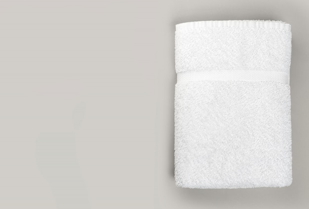 Vista superior de la toalla de baño blanca limpia doblada sobre fondo gris con espacio de copia