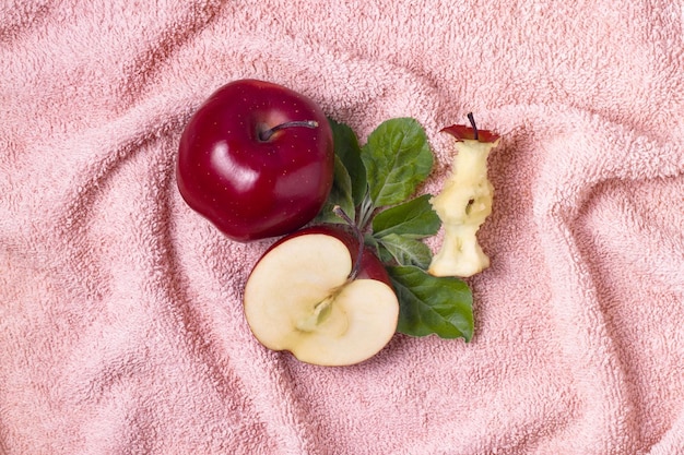Foto vista superior de toda la mitad de la manzana y el núcleo de la manzana con hojas verdes en la toalla plana de piel rosa