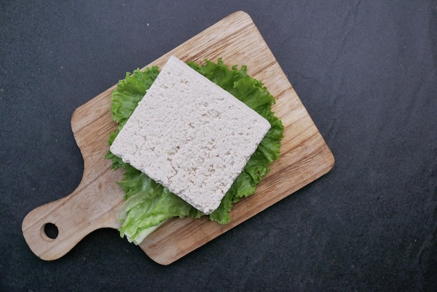 Vista superior de tofu en una tabla de cortar sobre fondo negro