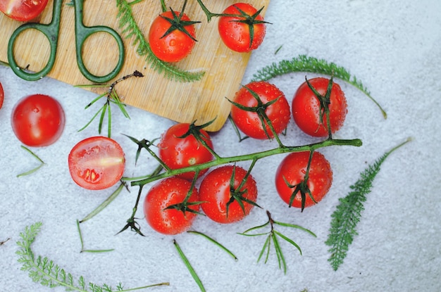 Vista superior de tomates cherry rojos frescos con hierbas sobre un fondo blanco en la mesa de cerca. endecha plana