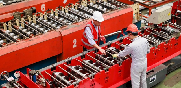 Vista superior Trabajador ingeniero de fábrica que opera una máquina de techo de chapa metálica en la fábrica de fabricación de la industria pesada Trabajador en casco de seguridad en las instalaciones industriales de la fábrica