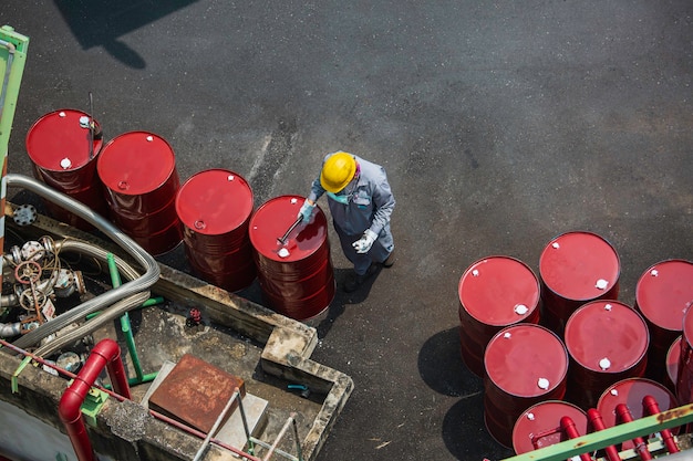 Vista superior trabajador masculino registro de inspección tambor aceite stock barriles rojo vertical o químico para la industria.