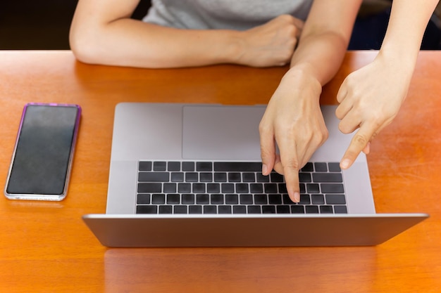 Vista superior del trabajo en equipo de la mujer apuntando la mano a la pantalla del portátil