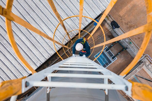 Vista superior trabalhador masculino desce a escada inspeção tanque inoxidável trabalho em altura arnês de segurança