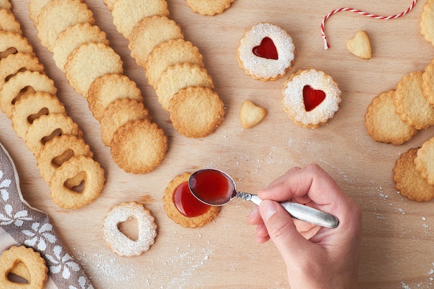 Vista superior de las tradicionales galletas Linzer de Navidad rellenas de mermelada de fresa sobre tabla de madera.