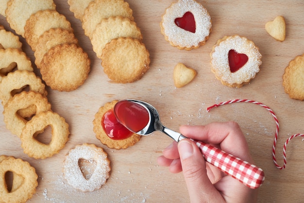 Vista superior de las tradicionales galletas de Navidad Linzer rellenas de mermelada de fresa en tablero de madera