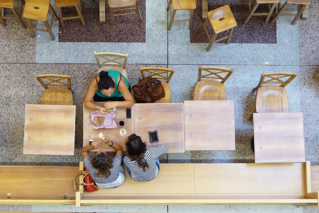 Vista superior de tres amigas en el café durante la pausa para el almuerzo Mesas de madera y estilo retro Concepto de amistad y pausa para el almuerzo