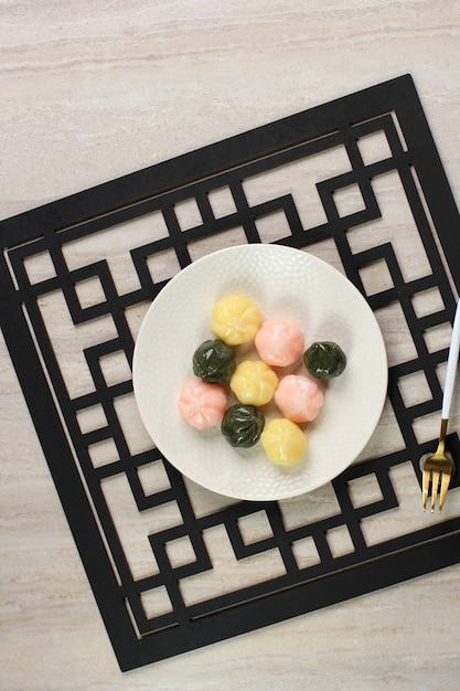 Vista superior de tres colores Kkultteok es un pastel de arroz en forma de bola relleno con miel y sirope de sésamo, pastel tradicional coreano para el día de Chuseok. Servido en plato blanco