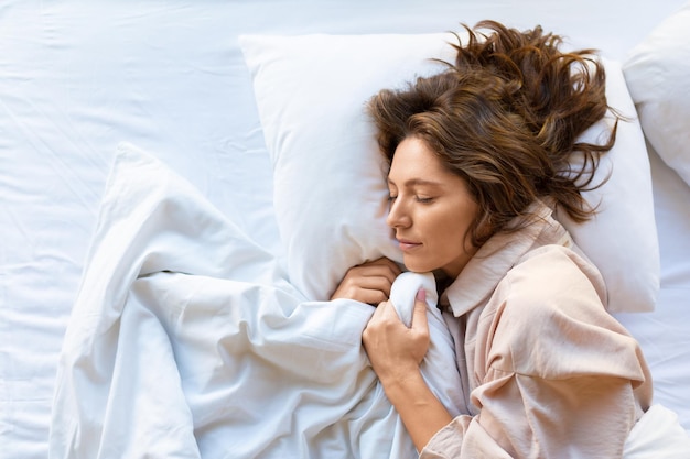 Vista superior uma jovem está dormindo abraçando um cobertor o conceito de recuperação e sono saudável