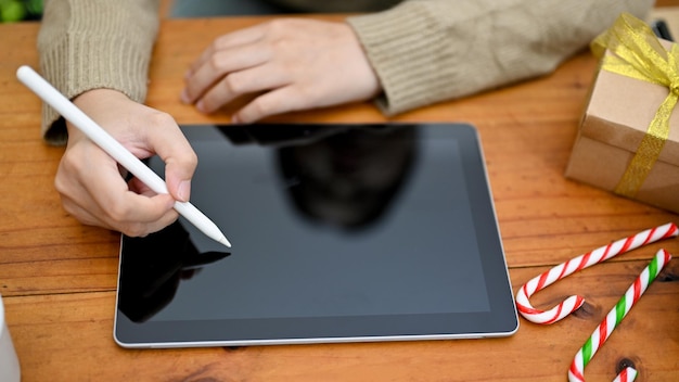Foto vista superior uma mulher usando seu tablet digital na tela preta do tablet de mesa de madeira