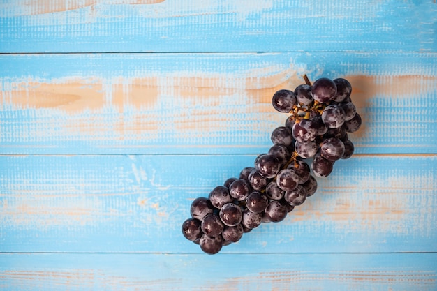 Foto vista superior de uvas negras en mesa de madera azul