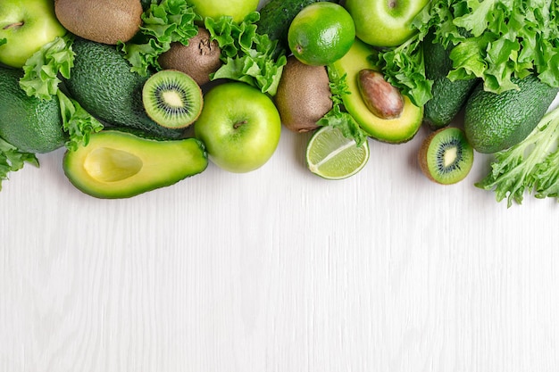 Vista superior de varias verduras y frutas verdes en el fondo de madera blanca con espacio para copiar