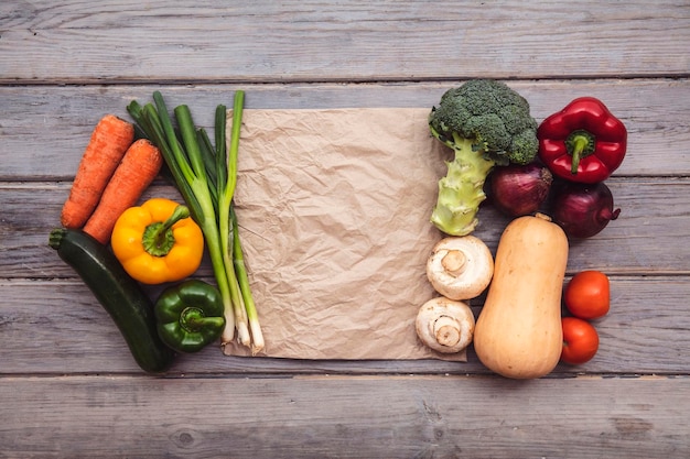 Vista superior de varias verduras orgánicas frescas con una bolsa de papel marrón en blanco