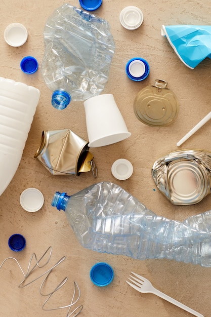 Vista superior de varios elementos de basura colocados en una composición mínima sobre cartón, concepto de clasificación y reciclaje de residuos