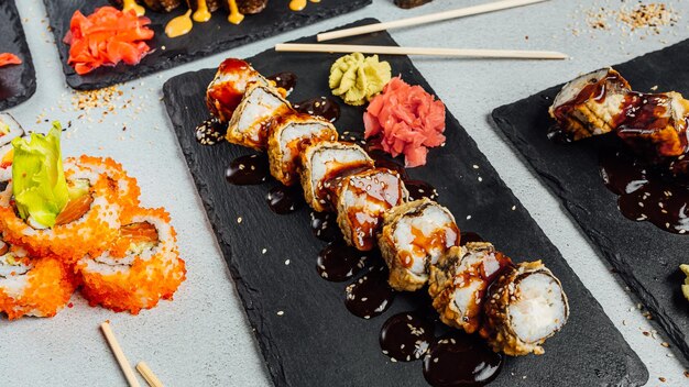 Foto vista superior de varios platos de coloridos rollos de sushi dispuestos en círculo y servidos con salsas