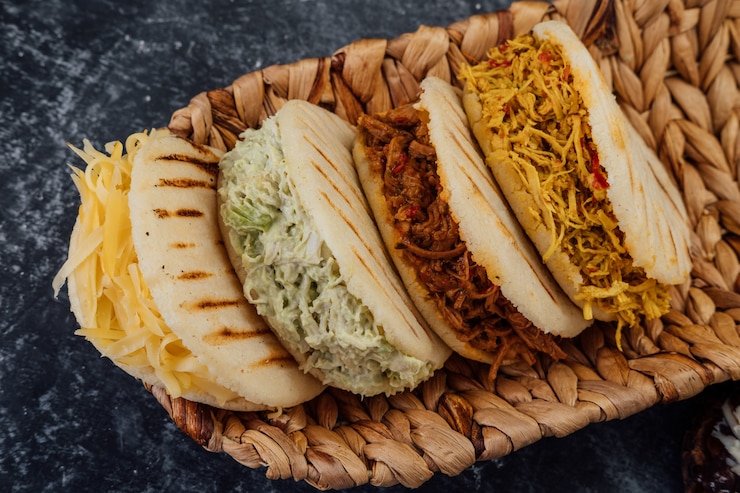 Foto vista superior de varios tipos de arepas típicas venezolanas en una canasta tejida