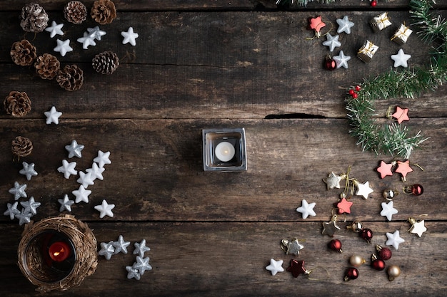 Vista superior de una vela encendida en un escritorio de madera rústica en medio de la decoración navideña y de temporada.