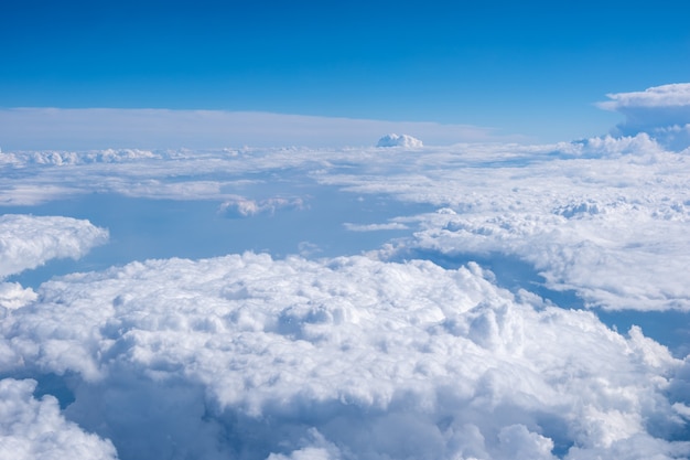 Vista superior desde la ventana del avión sobre hermosas nubes blancas mullidas cúmulos en un cielo azul con un sol brillante. Fondo de cielo abstracto perfecto, papel tapiz, diseño.