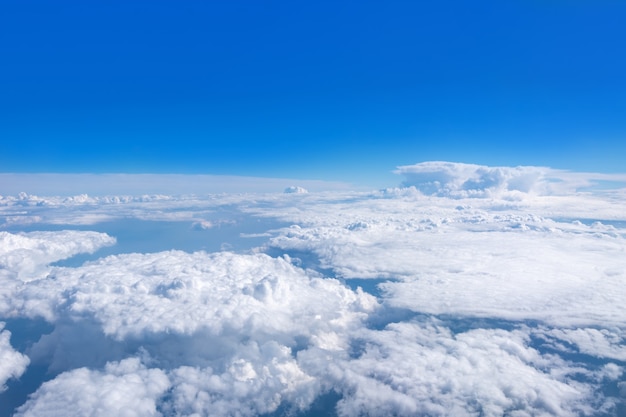 Vista superior desde la ventana del avión sobre hermosas nubes blancas mullidas cúmulos en un cielo azul con un sol brillante. Fondo de cielo abstracto perfecto, papel tapiz, diseño.