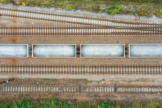 Vista superior de las vías del tren con vagones con piedra en día de verano