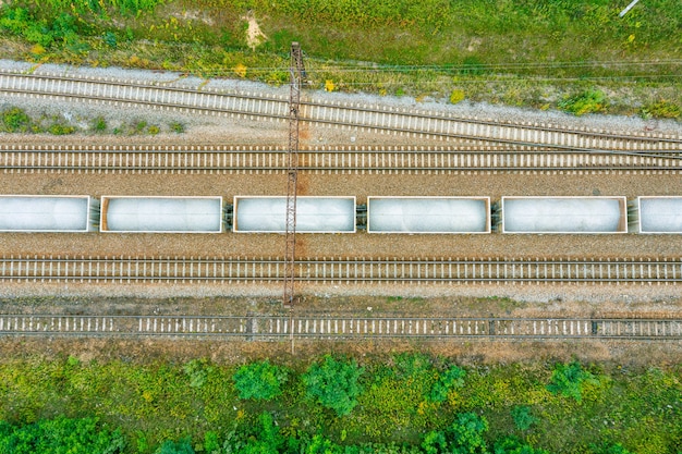 Vista superior de las vías del tren con vagones con piedra en día de verano