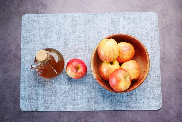 Vista superior de vinagre de manzana en botella de vidrio con manzana verde fresca en la mesa