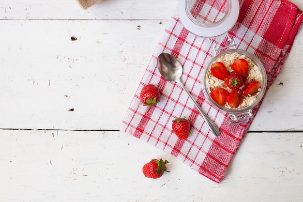 Vista superior de yogur dulce con fresas maduras frescas para el desayuno en la vieja mesa de madera con rojo