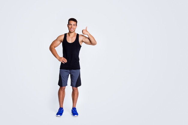 Foto vista del tamaño del cuerpo de cuerpo entero de un tipo musculoso deportivo alto fuerte que muestra el anuncio thumbup