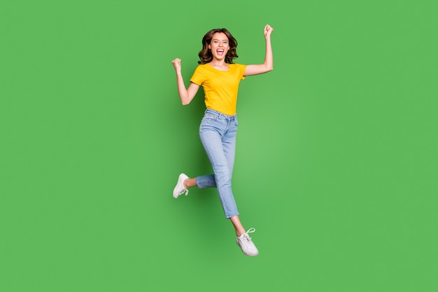 Vista del tamaño del cuerpo de longitud completa de alegre alegre niña afortunada saltando celebrando divertirse