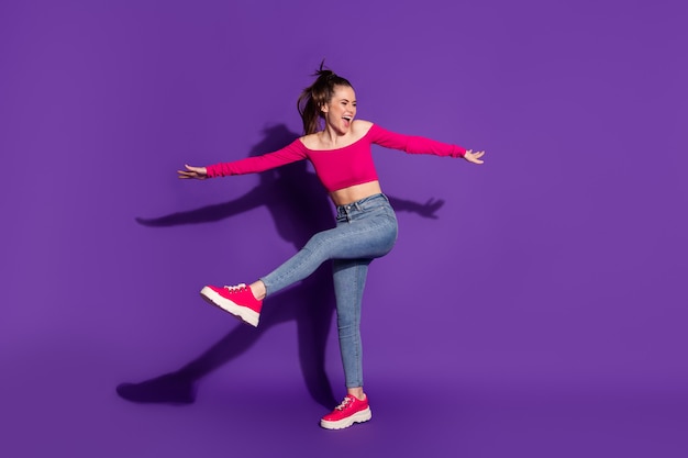 Vista del tamaño del cuerpo de longitud completa de la atractiva chica alegre despreocupada esbelta bailando divirtiéndose aislado sobre fondo de color violeta brillante