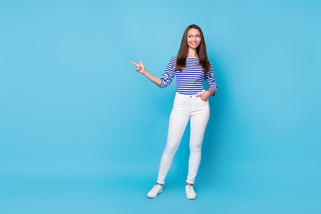 Vista del tamaño del cuerpo de longitud completa de ella, atractiva chica alegre y atractiva que demuestra el anuncio publicitario copia espacio en blanco vacío lugar aislado brillante vivo brillo vibrante fondo de color azul