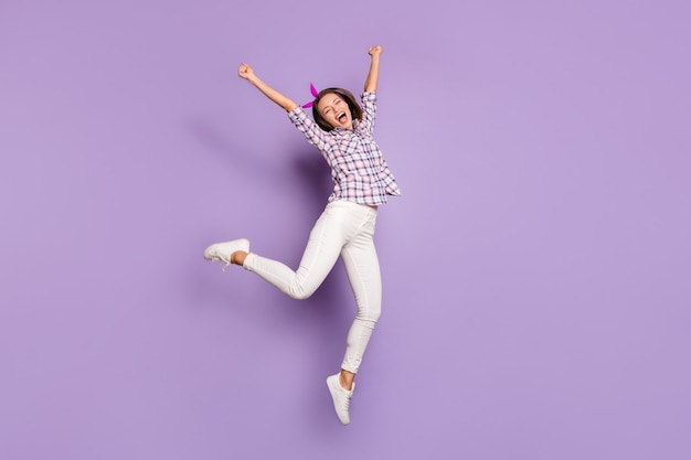 Vista del tamaño del cuerpo de longitud completa de niña saltando divirtiéndose celebrando el logro