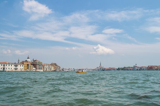 Vista del terraplén del Canal de Venecia en un cálido día de verano, con barcos flotantes y casas antiguas, Venecia