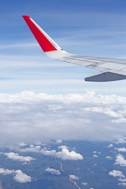 Vista de la tierra, el cielo, las nubes y el ala del avión desde la ventana