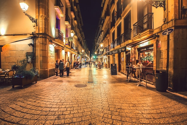 Vista típica de la calle pequeña de San Sebastián con animados bares de tapas y restaurantes por la noche.