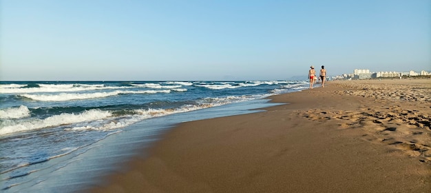 Vista de tiro de una mujer hermosa caminando por la playa cerca del mar