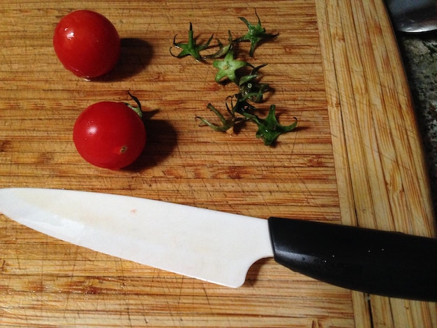 Foto vista de tomates en ángulo alto con un cuchillo en la tabla de cortar