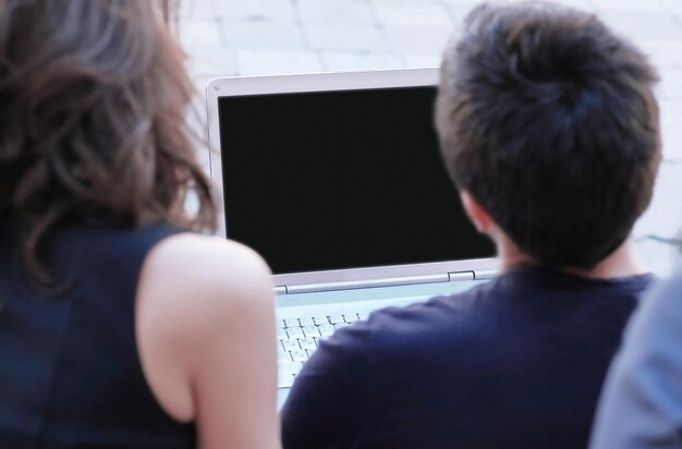 Vista traseira alguns alunos olhando para a tela do laptop