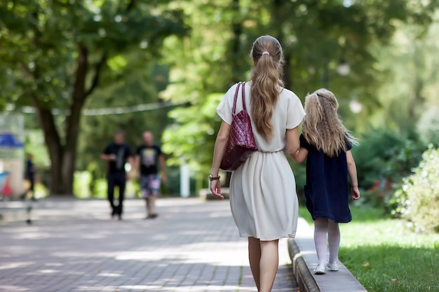 Vista traseira da jovem mãe andando com menina