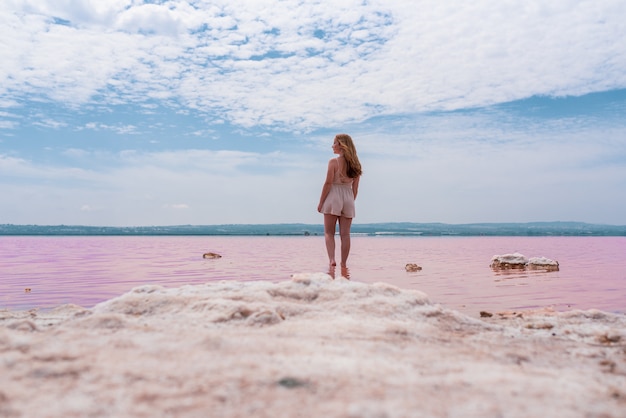 Vista traseira da mulher adolescente bonito vestindo roupas de verão no lago rosa